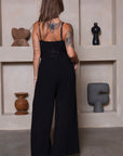 Zwarte lange jumpsuit met strik, spaghettibandjes en wijde pijpen.