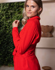 Stijlvol rood damespak met blazer met strikceintuur en bijpassende pantalon, perfect voor een zakelijke look.