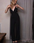 Zwarte jumpsuit met spaghettibandjes en uitsnijdingen aan de zijkanten, losvallend aan de onderkant voor een comfortabele pasvorm.