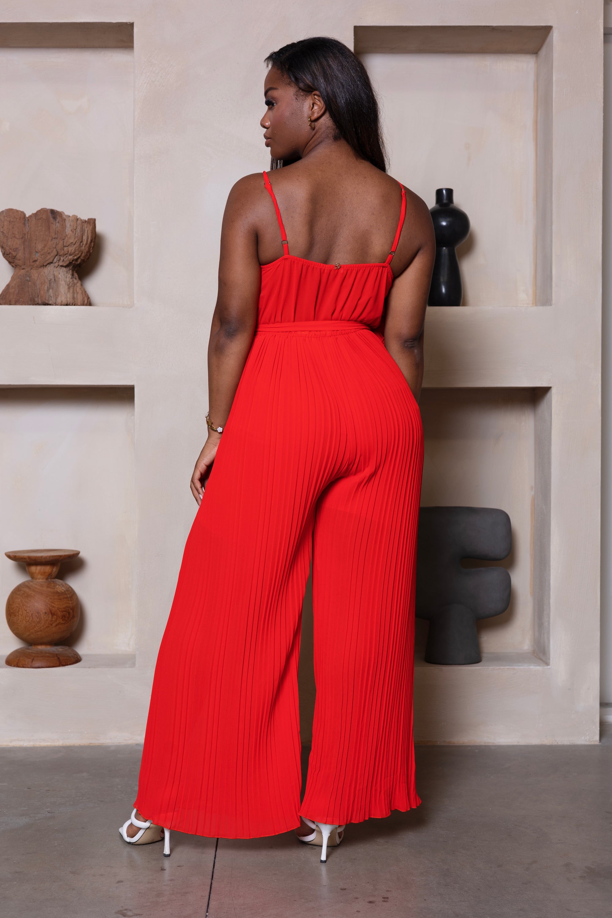 Rode lange jumpsuit met strik, spaghettibandjes en wijde pijpen. 