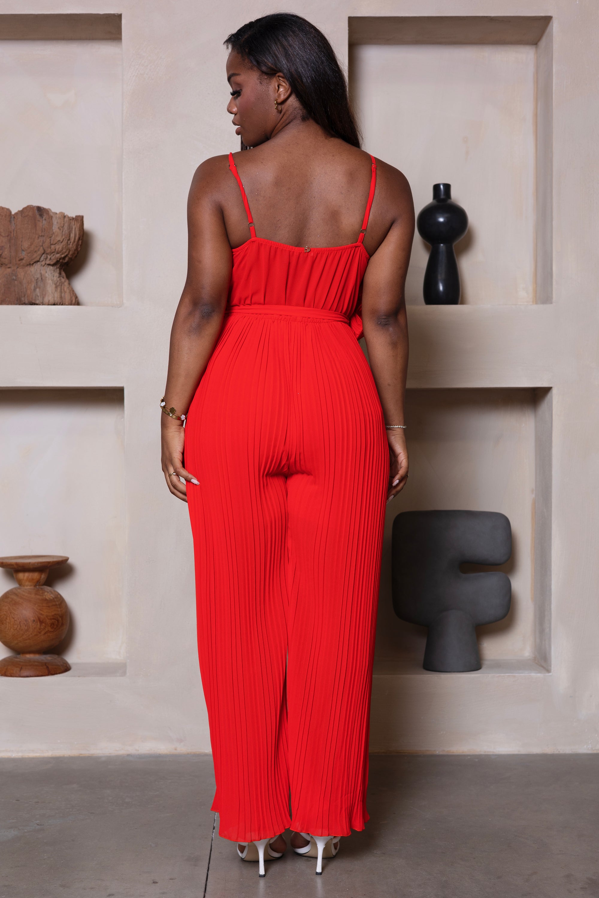 Rode lange jumpsuit met strik, spaghettibandjes en wijde pijpen. 